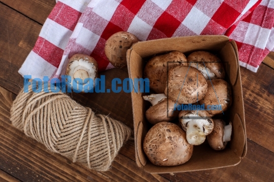 Baby bella mushrooms inside paper container on wooden table with