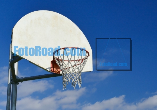 Basketball net in a wooden basketball hoop with blue sky and clo