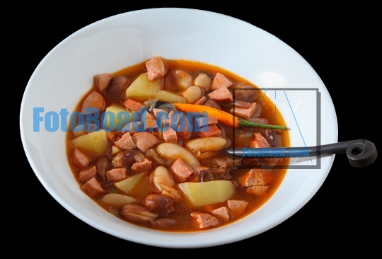 Beans soup with hot dog and potatoes on  black background  