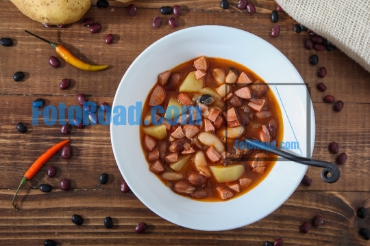 Beans soup with hot dog and potatoes on rustic wooden table desk