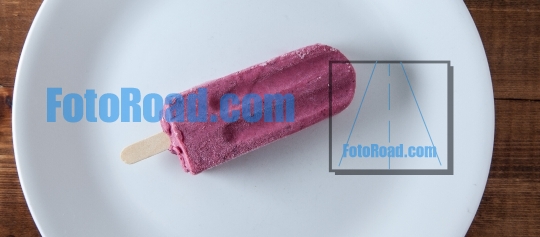 Blueberry ice popsicle on white plate