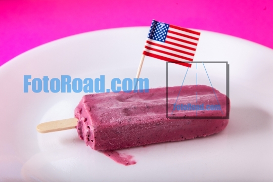 Blueberry ice popsicle with american flag on white plate with pu