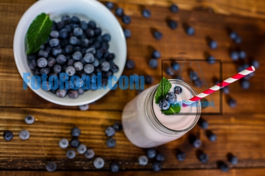 Blueberry smoothie with mint leaf and straw on wooden backround 