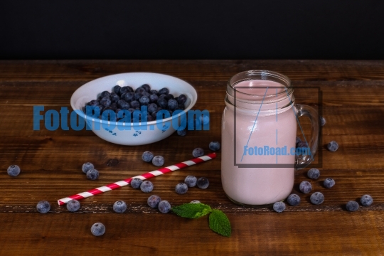 Blueberry smoothie with straw on wooden backround 