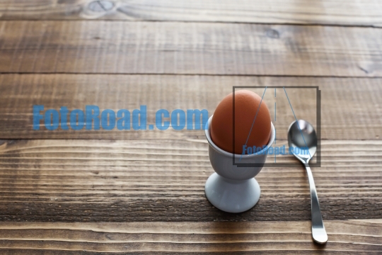 Boiled egg on wooden table with spoon 