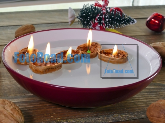 Candle inside walnuts shell floating on water inside bowl