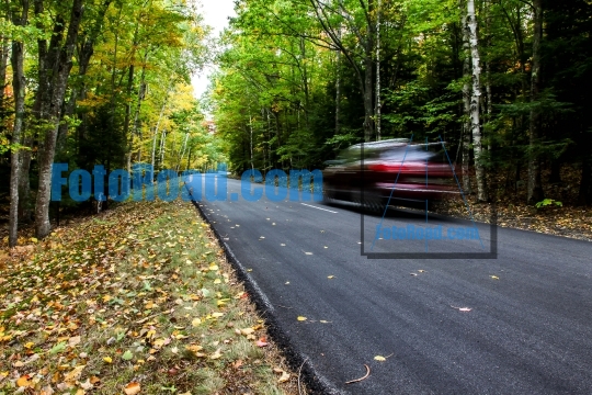 Car driving thru autumn road