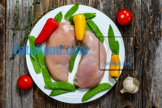 Chicken brests with vegetables on rustic wooden table