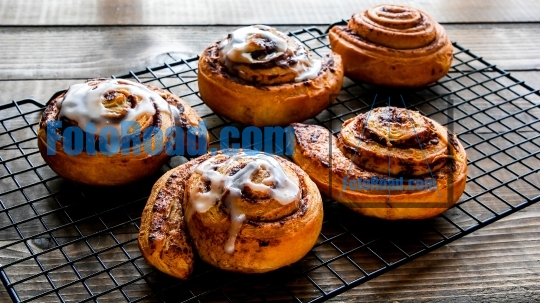 Cinnamon rolls with vanilla icing on cooling rack
