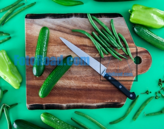 Cutting board with vegetables on green background
