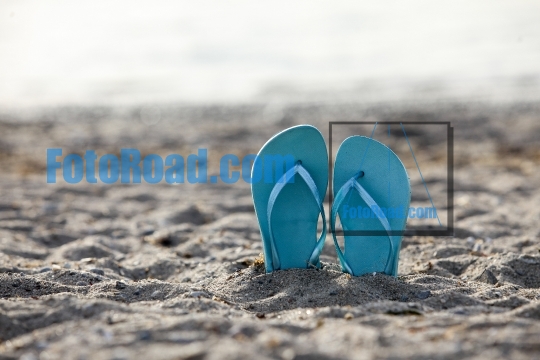 Flip flops on beach sand with focus on foreground