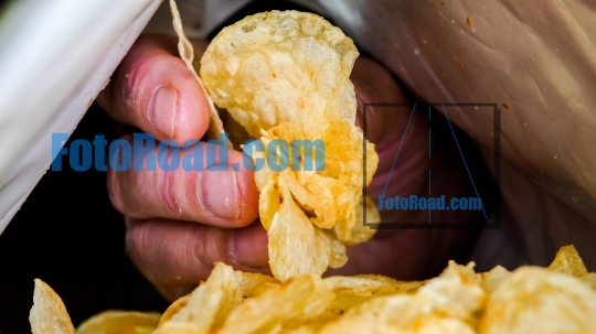 Hand is picking potato chips from bag