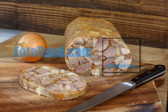 Home made head cheese with knife and onion on wooden background