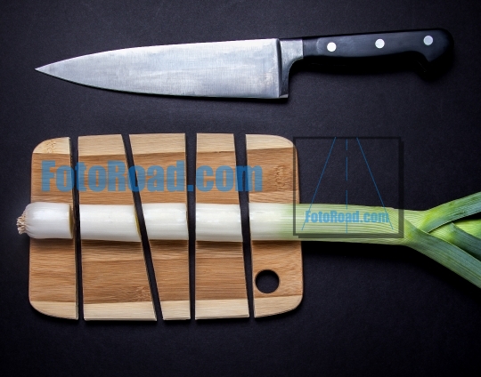 Knife with leek and wooden cutting board