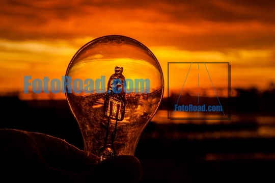 Light bulb in hand against colorful sunrise 