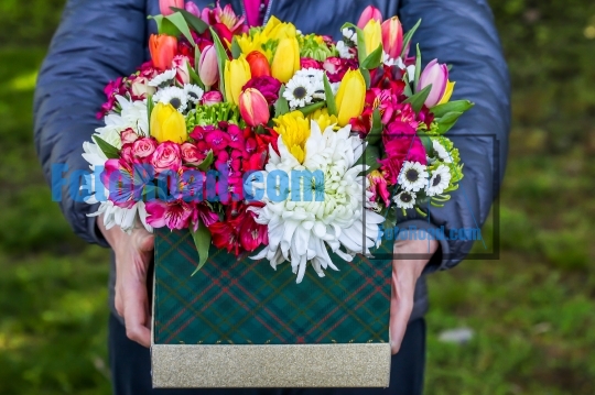 Person is holding box with beautiful flovers outdoor