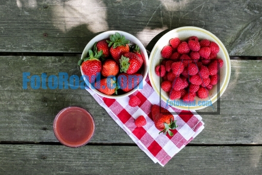 Raspberries   strawberries inside bowls on wooden table with vit