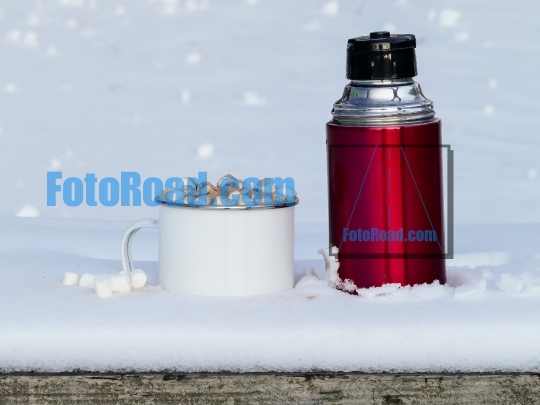 Red thermos with hot chocolate drink outside