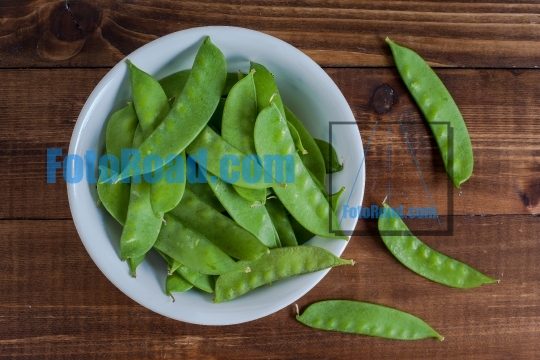 Snow peas inside bowl on wooden table