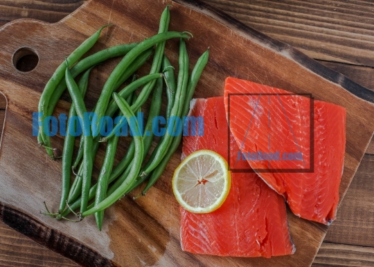 Sock eye salmon with organic green beans and lemon on wooden cut
