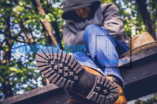 Tired hiker sitting on table with trees behind and boots view  