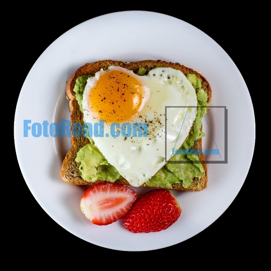 Toast with avocado and egg in heart shape on black background