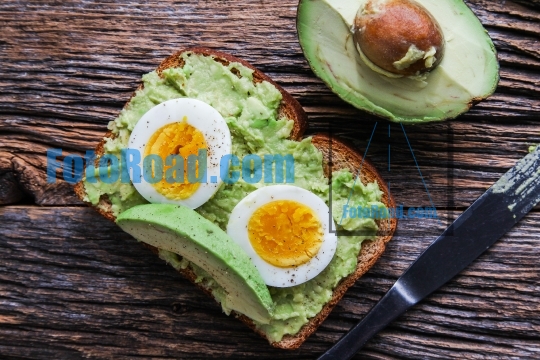 Toast with mashed avocado and eggs on rustic wooden table with k