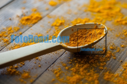 Turmeric powder in wooden spoon on wooden rustic looking table