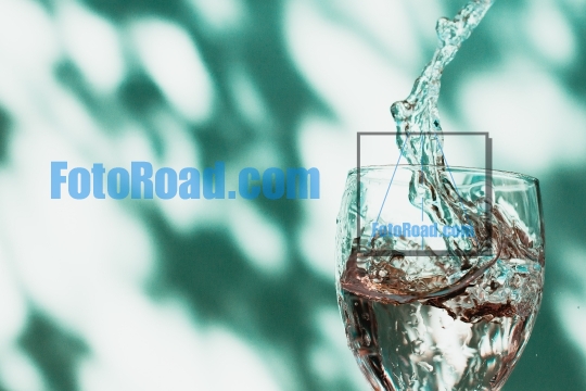 Water splash with glass on green background