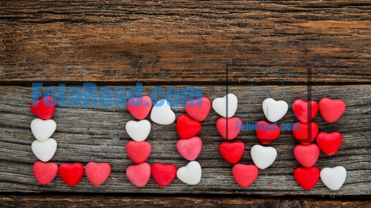 Wooden background with word Love made from candy hearts