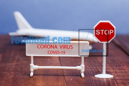 Corona virus sign on foreground with toy aeroplane in back