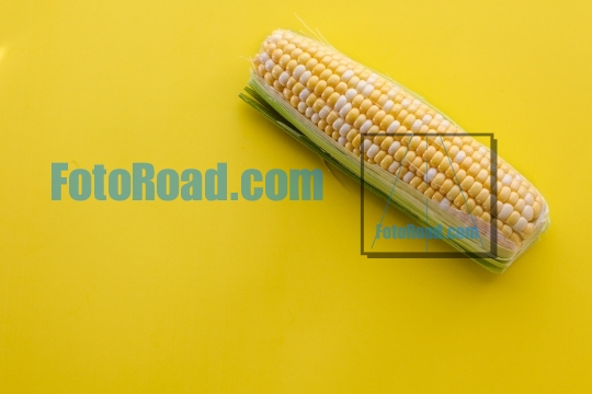 Yellow sweet corn on yellow background table top
